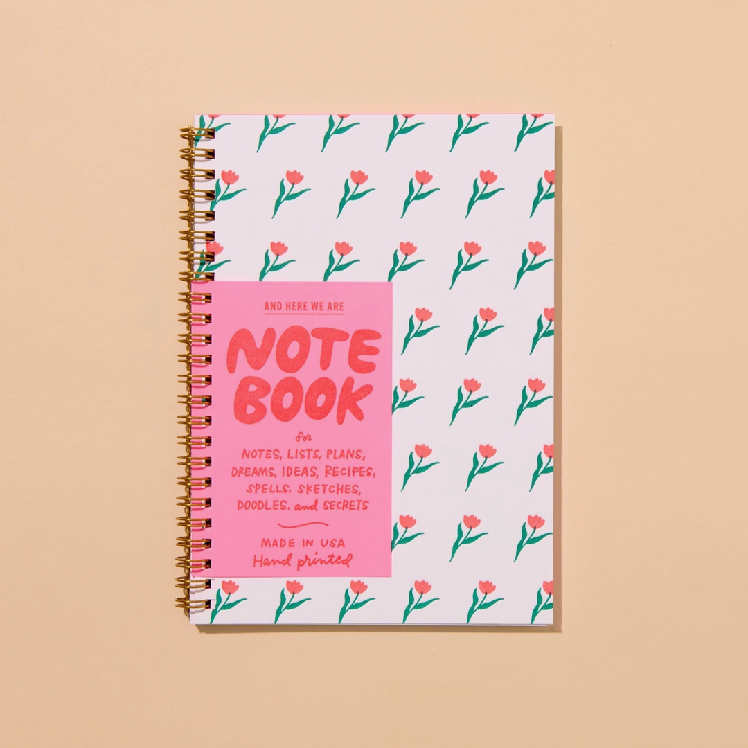 Notebook with floral pattern and pink label on beige background
