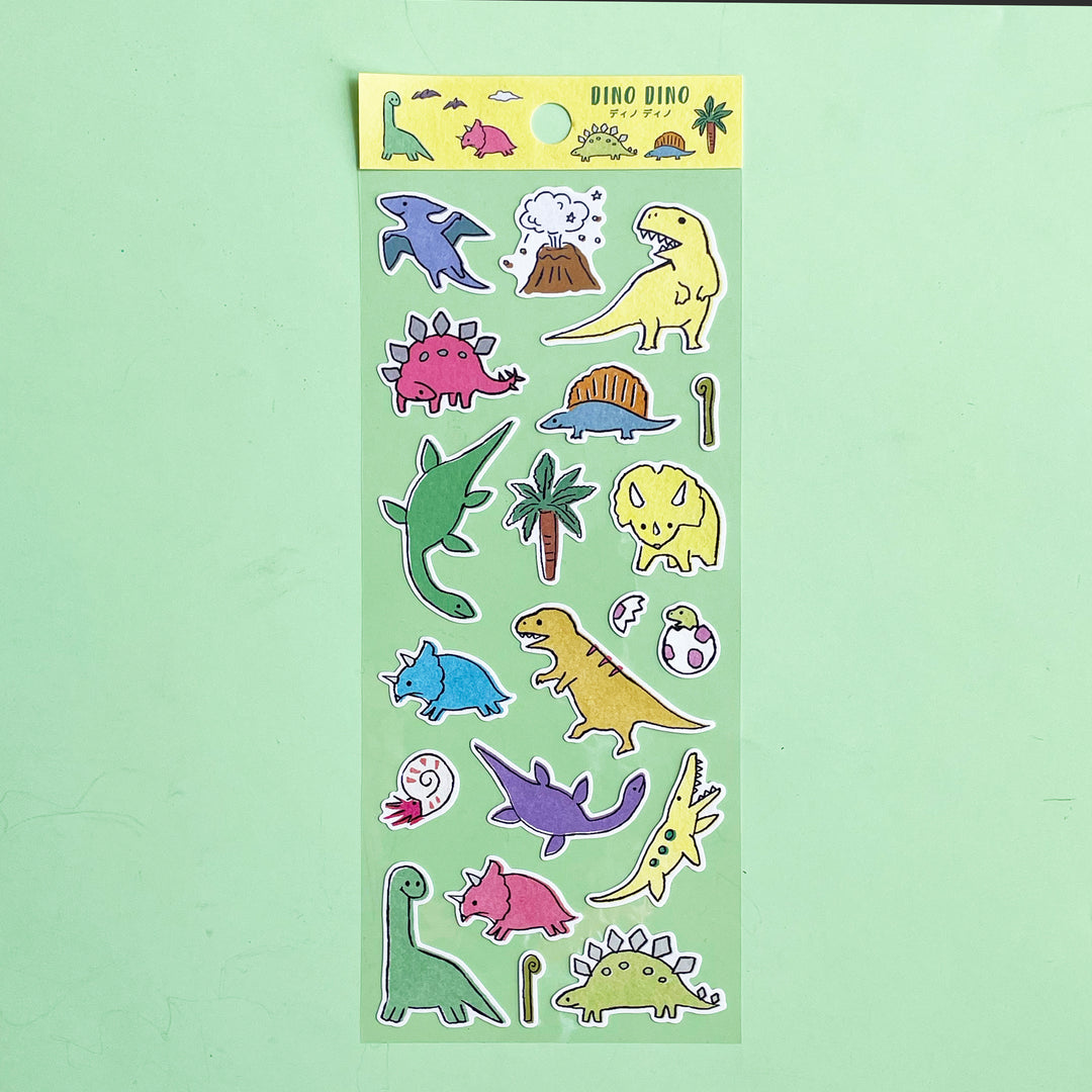 A sheet of colorful , cartoon style dinosaur stickers on a light green background. 