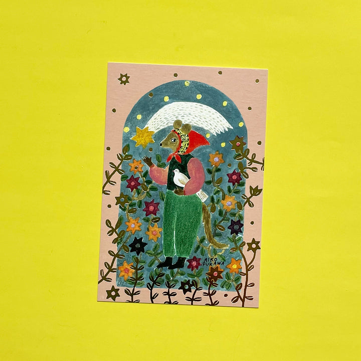 A mauve post card with an anthropomorphic mouse in a red bonnet holding a dove under a shooting star. Gold vines and flowers surround the character.