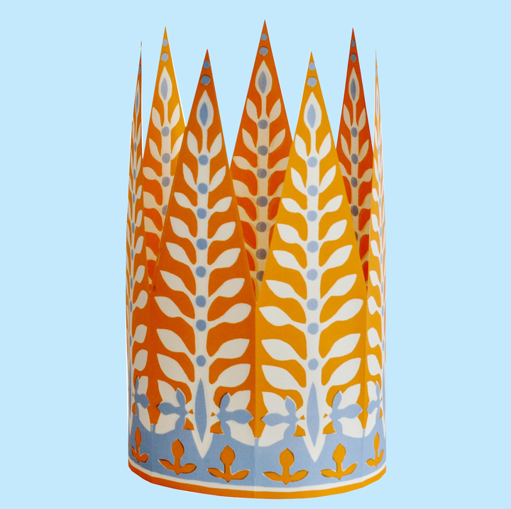 Colorful paper crown with tall peaks and a whimsical leaf pattern displayed on a light blue background. 