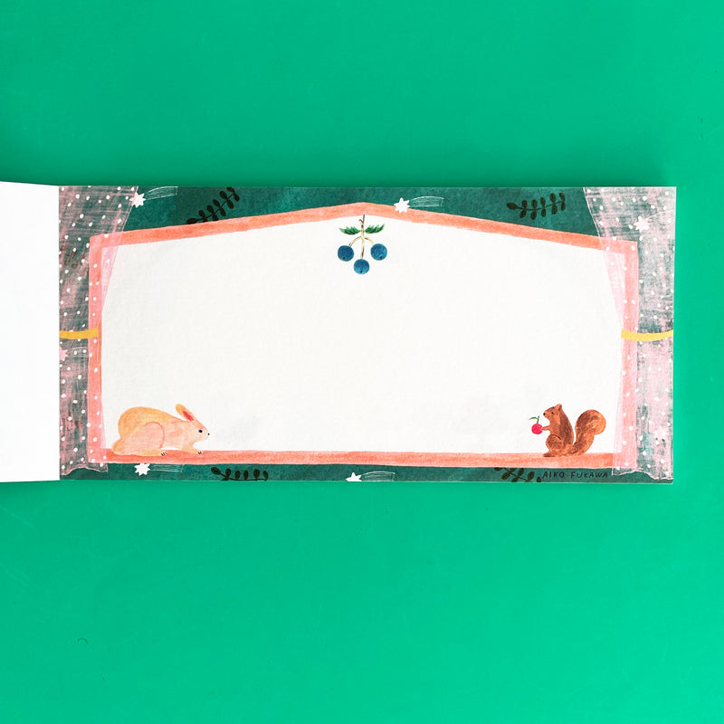 This page of the memo pad features a squirrel and a rabbit on a peach colored window sill. The window is surrounded by sheer polka dot curtains and teal wallpaper.