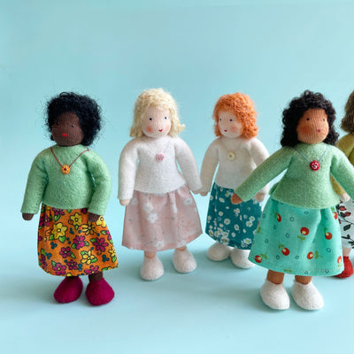 4 dolls with various skin tones and hair colors. 2 wear mint green felt tops, and 2 wear white. All have different floral patterned skirts.