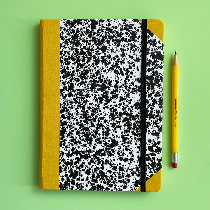 Notebook with black and white pattern and yellow binding on a green background