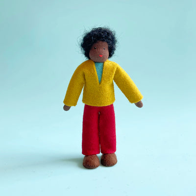 A 5.25-inch cotton doll with dark skin and black curly hair wearing a yellow felt top and yellow felt pants.