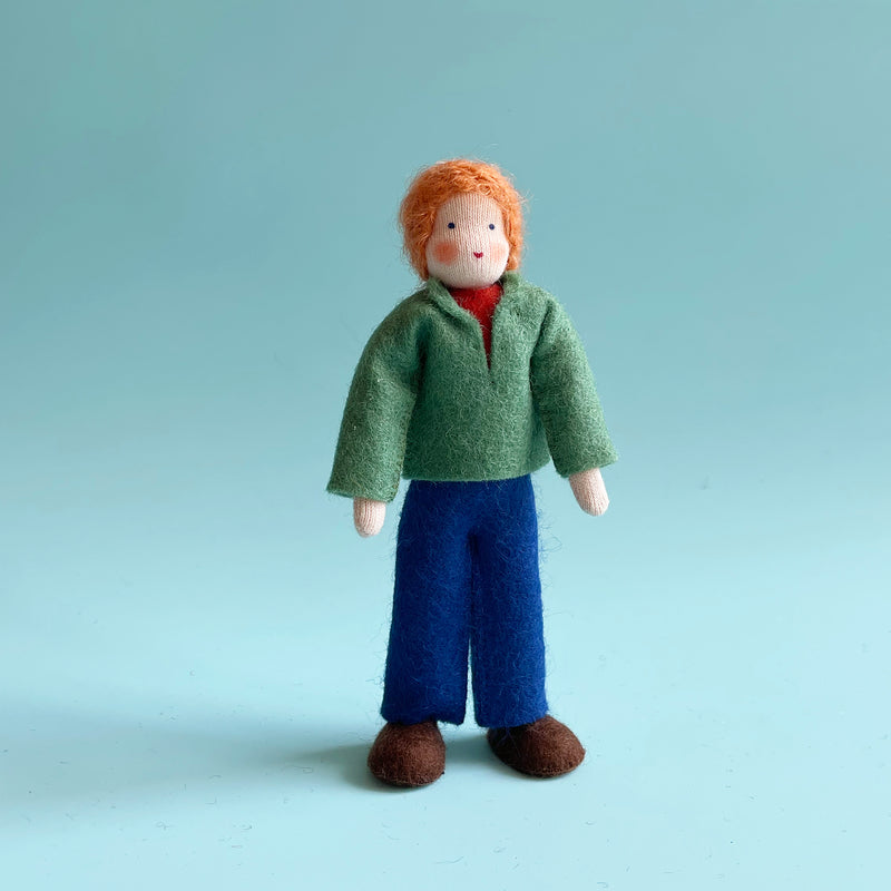 A 5.25-inch cotton doll with light skin and orange hair wearing a green felt top and blue felt pants.