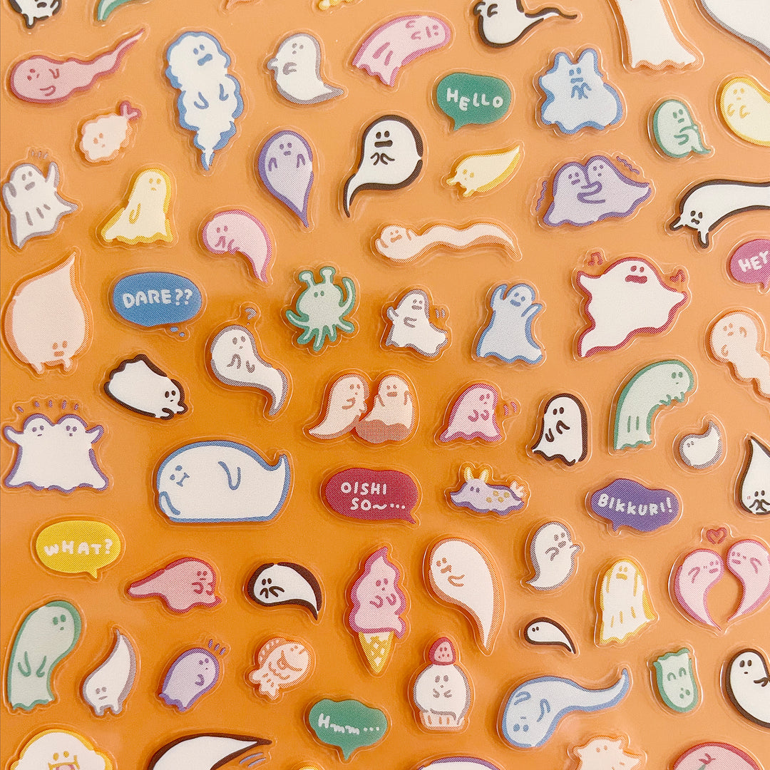 Collection of colorful ghost-shaped stickers with various expressions and text on an orange background