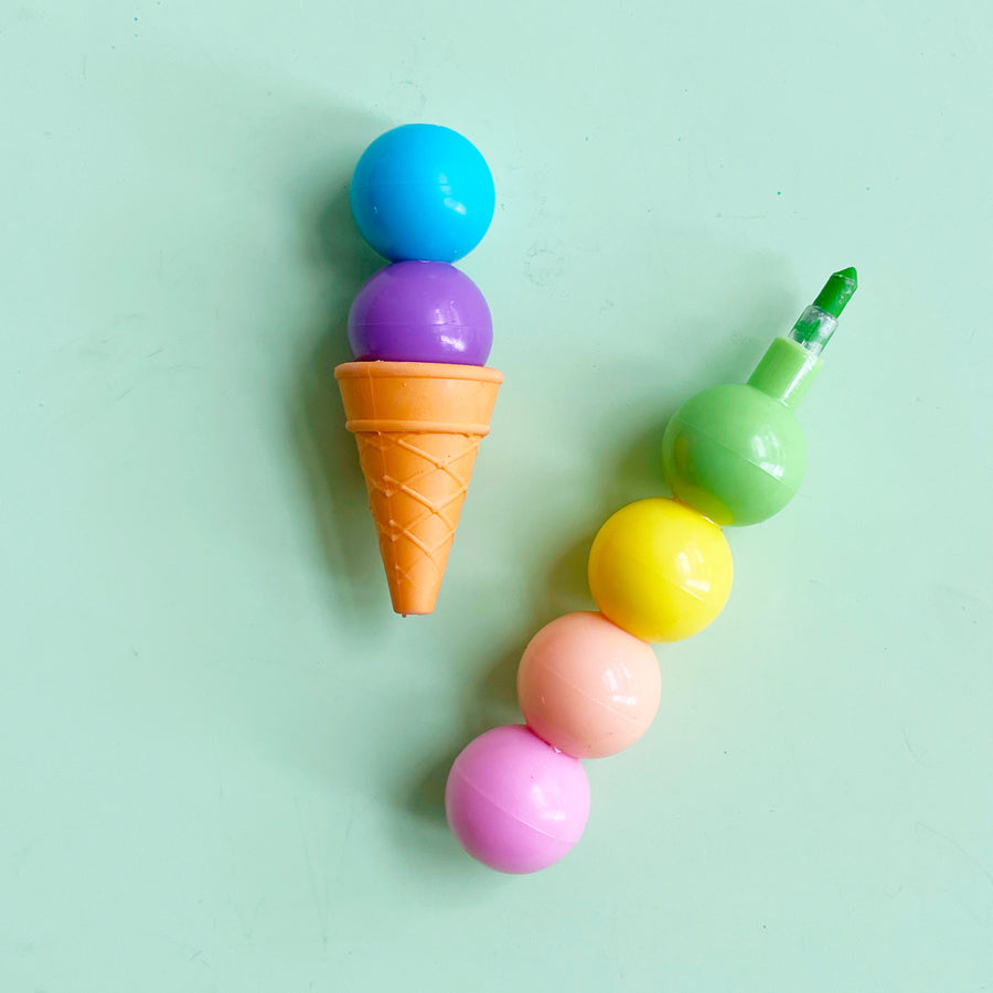 A stackable set of crayons that look like an ice cream cone displayed against a light green background. 