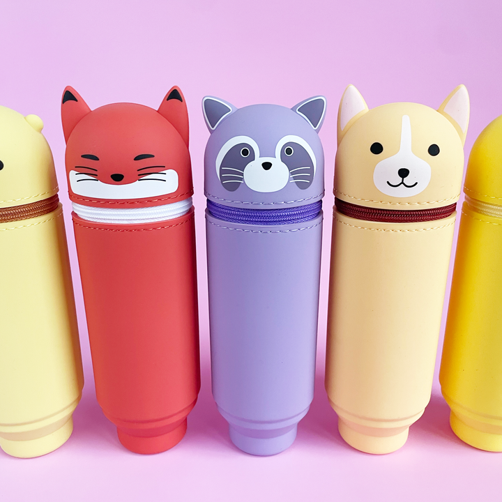 Five colorful animal-themed pen cases on a pink background