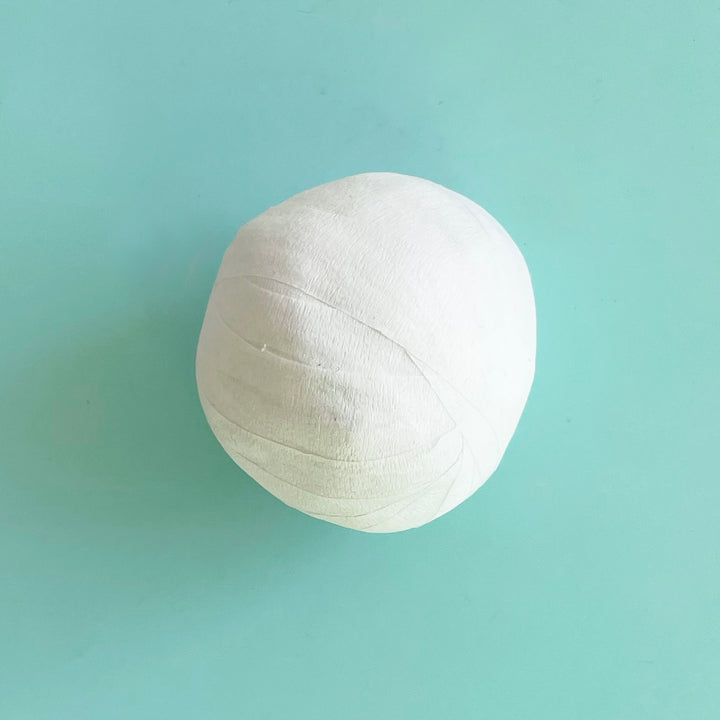 One small white surprise ball on a light blue bacground. 