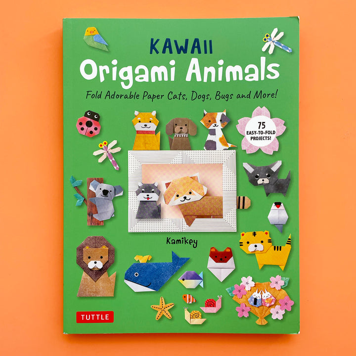 Kawaii Origami Animals book displayed on a bright orange background. The book cover features origami projects including a  koala, a red panda, cats, dogs and bugs. 