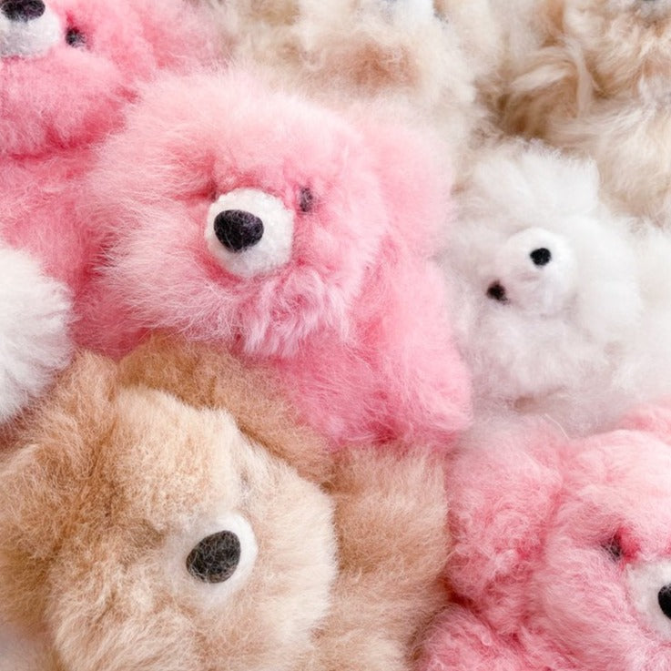 Close up pile of fluffy teddy bears in pink, brown and white. 
