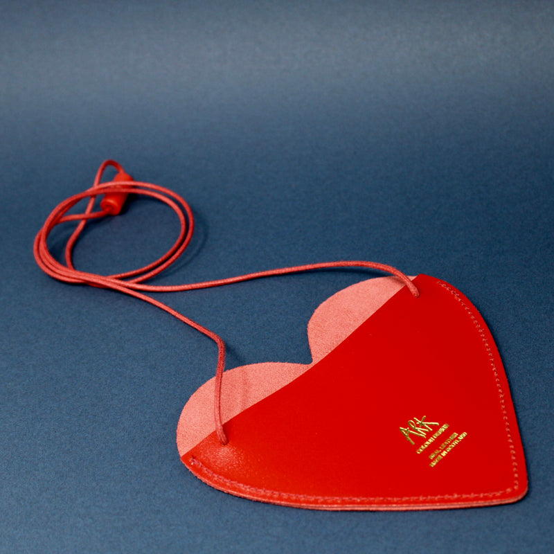 The back of a red heart shaped purse on a navy blue background
