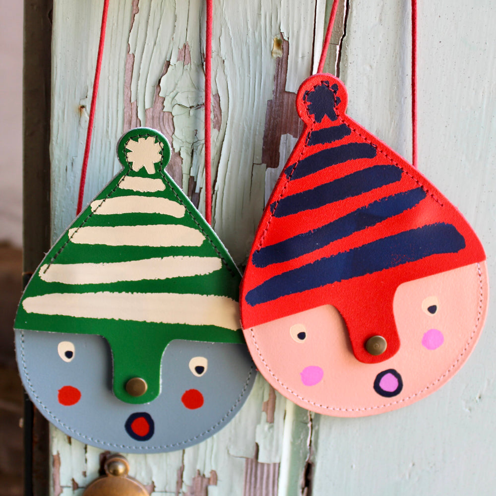 Two small leather bags hanging against a wall. 