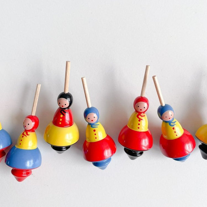 Five small babushka lady shaped tops in a horizontal line on a white background. 