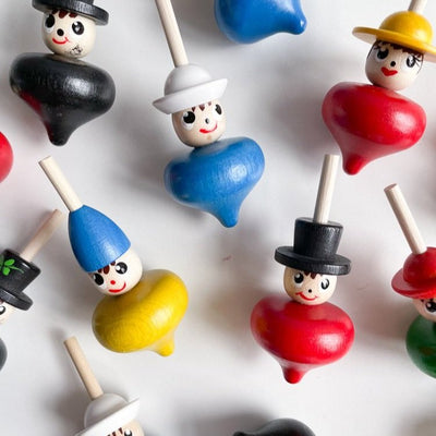 Several spinning tops shaped like people with hats on a white background. 