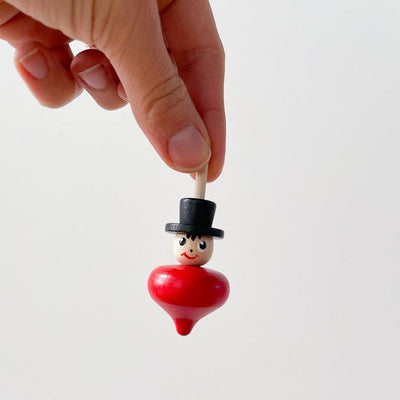 One spinning top being held by a large hand 
