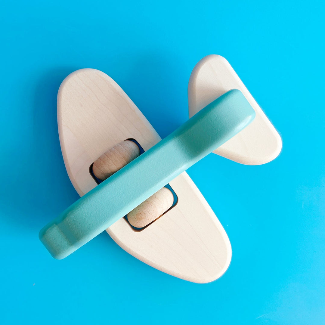 A top-down view of the wooden airplane with its blue painted body.