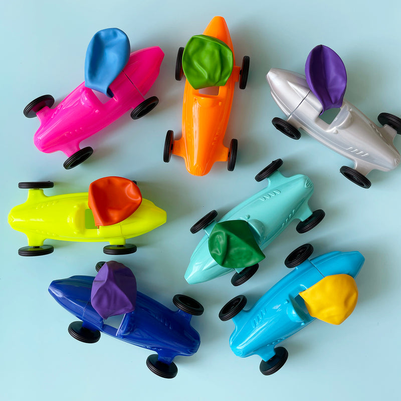 Several brightly colored plastic balloon cars with brightly colored balloons attached to their tops. 