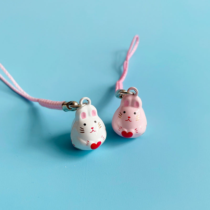 Two small bunny shaped bells on a blue background. 