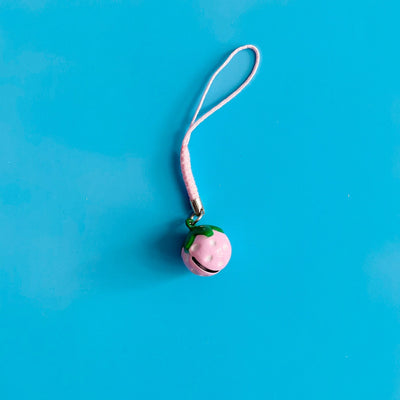 Small pink strawberry shaped bell against a blue background.