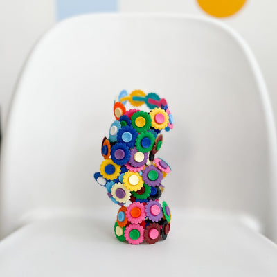 Several plastic flower bracelets staked on top of one another on a white background. 