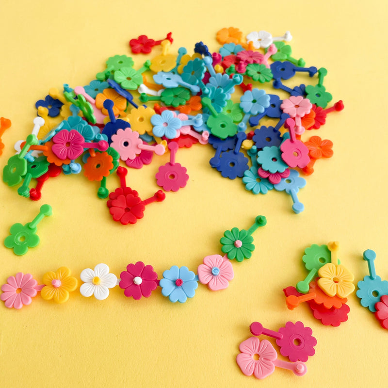 Close-up of small colorful flower clips spilled on a yellow background
