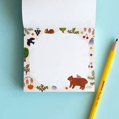 This page of the memo pad has white paper with a light grey border, with a bear, a bird, and plants.