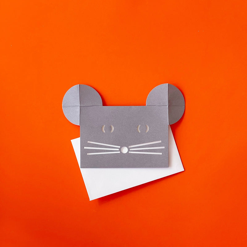 A gray mouse shaped greeting card sitting on top of a white envelope. 