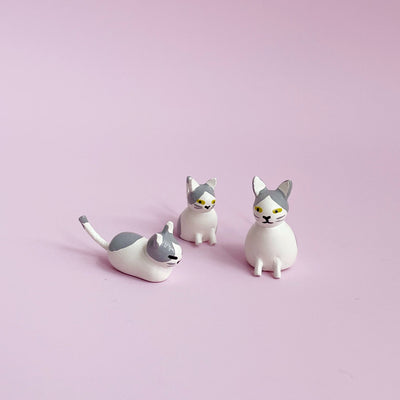 Wooden gray and white cat figurines on a pink background