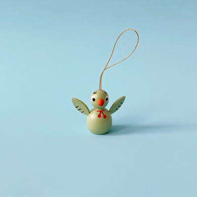 Light green wooden bird ornament on a blue background.