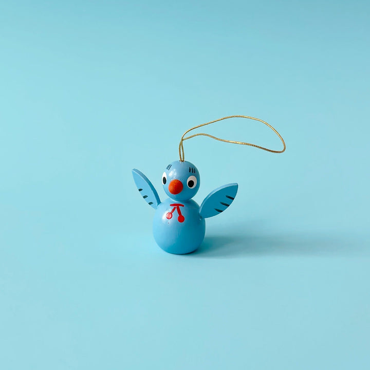 Light blue wooden bird ornament on a blue background. 