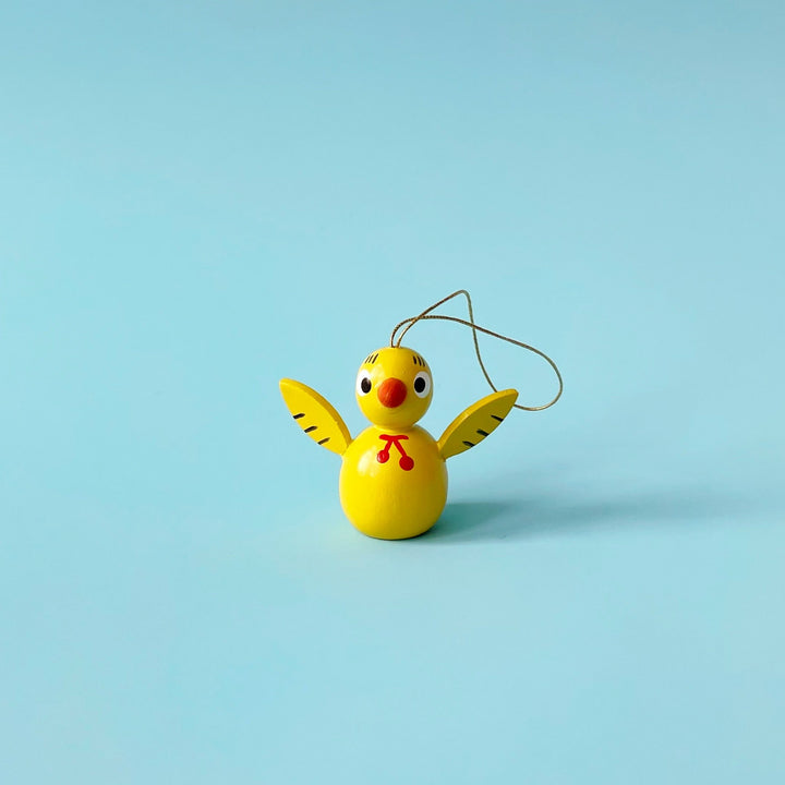 Yellow wooden bird ornament on a blue background.