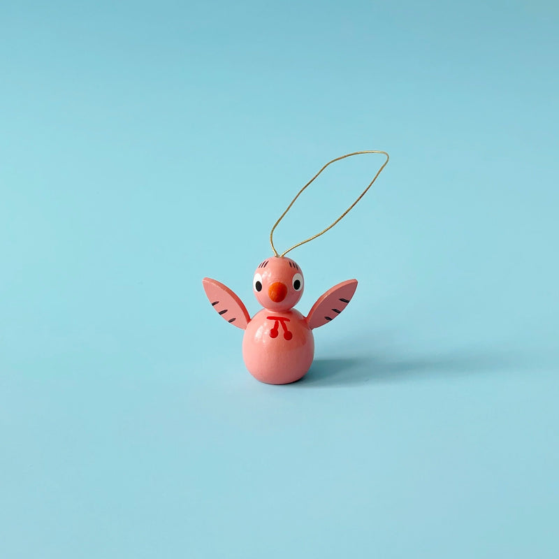 Pink wooden bird ornament on a blue background.