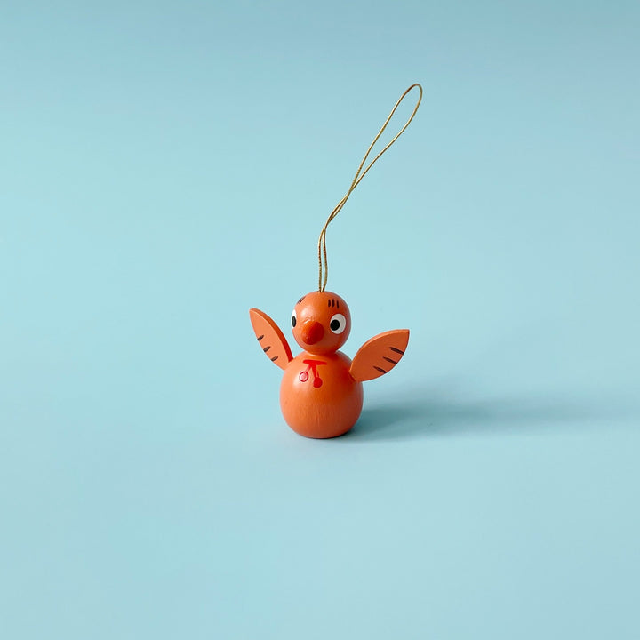 Orange wooden bird ornament on a blue background.