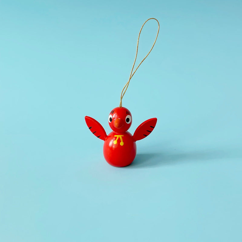 Red wooden bird ornament on a blue background.