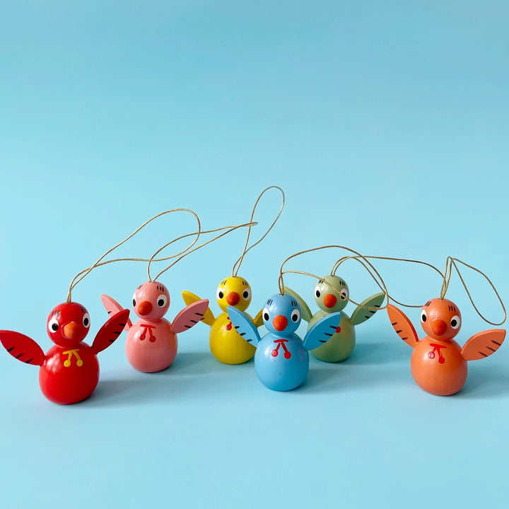 Several colorful wooden bird ornaments on a blue background.