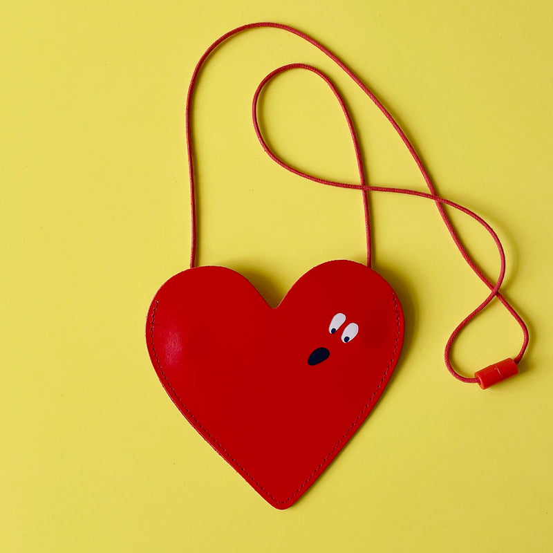Red heart shaped purse on a yellow background