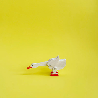 Wooden goose figurine on a yelllow background. 