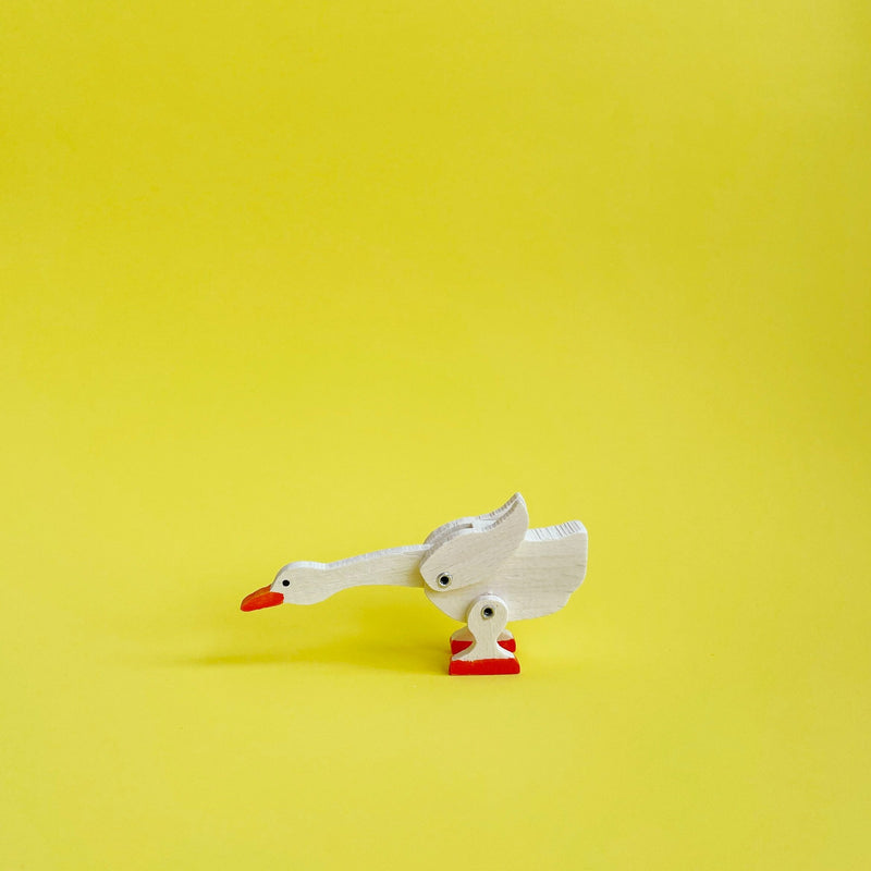 Wooden goose figurine on a yelllow background. 
