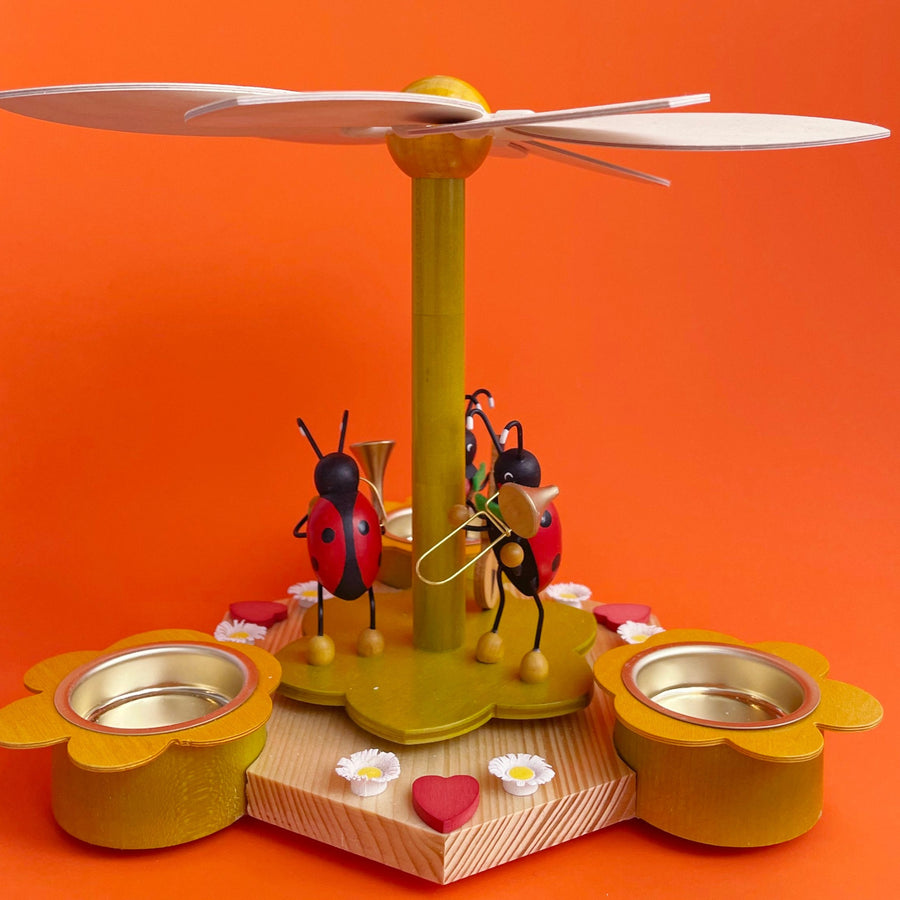 Wooden pinwheel decoration with ladybugs on an orange background. 