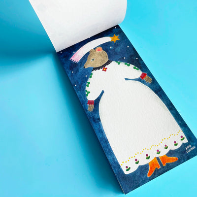 The memo pad is opened to a page featuring  a grey anthropomorphic mouse standing in a white dress under a shooting star.